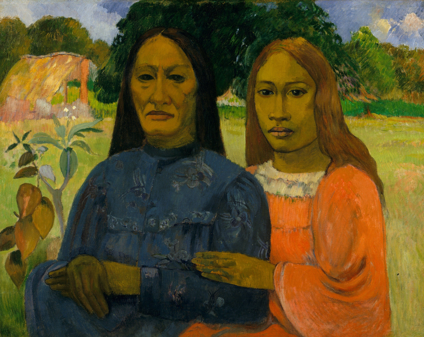 Two women standing side by side in a natural setting with trees and a building in the background.